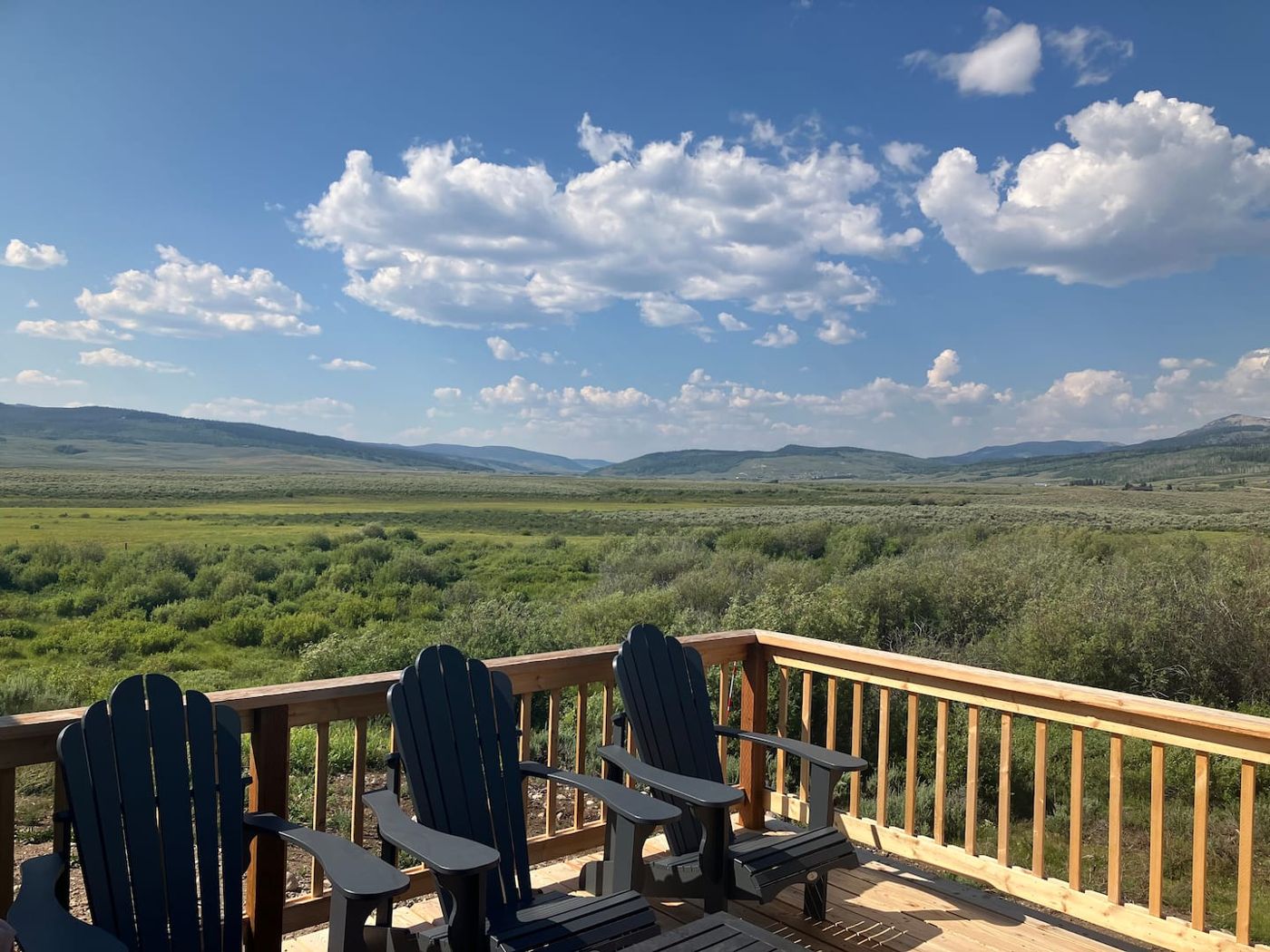 Adirondack chairs on the deck, the green valley beyond